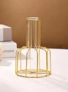 Gold wire vase on a white surface with a beige background